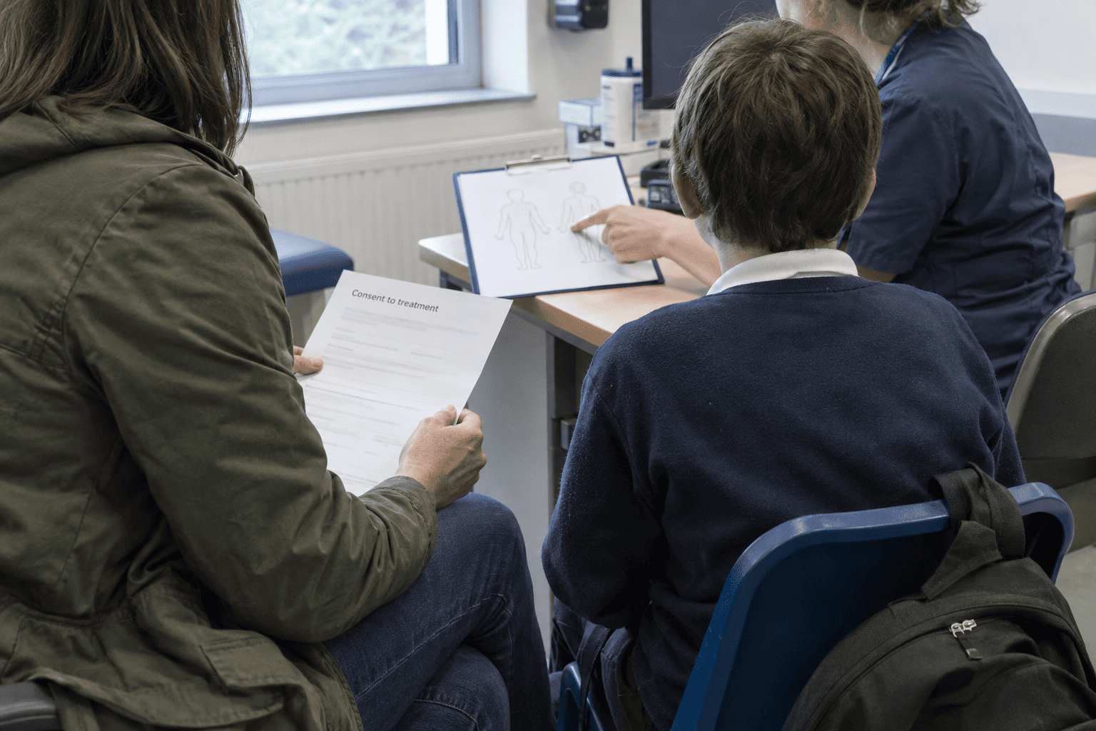 A parent and child discussing medical treatment with a healthcare professional