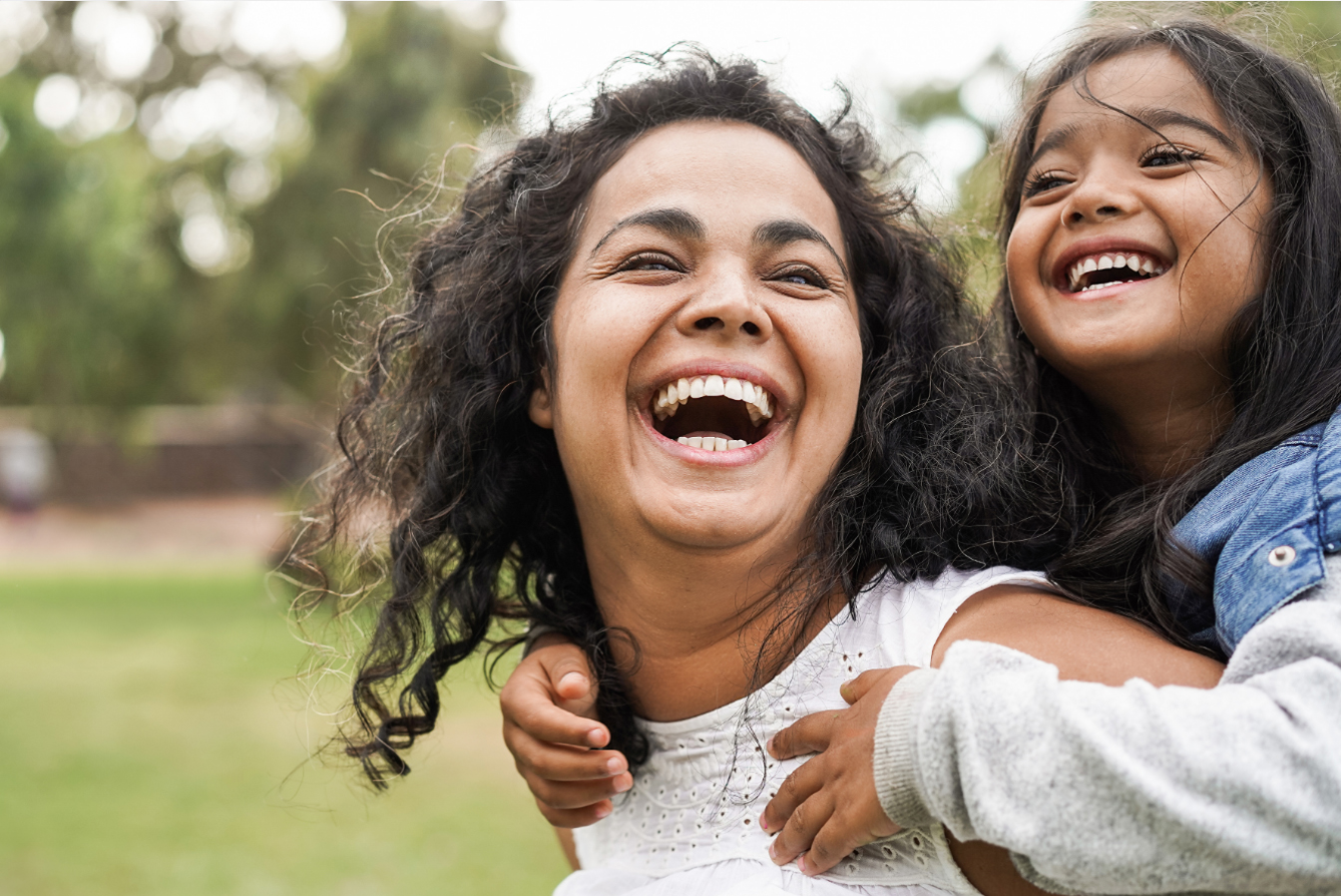 Daughter on mothers shoulders both laughing